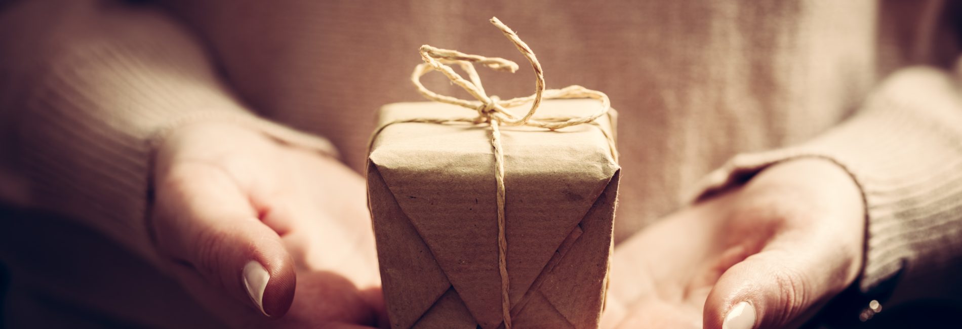 Giving a gift, handmade present wrapped in paper. Christmas time, vintage mood.