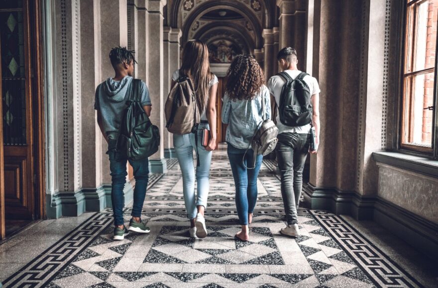 Four students walking down a hallway talking