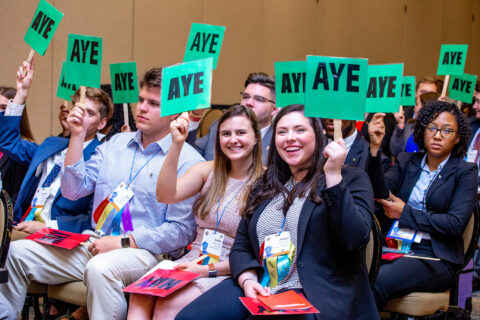 Members at Chapter Congress holding signs that read 'aye' while voting on legislation.